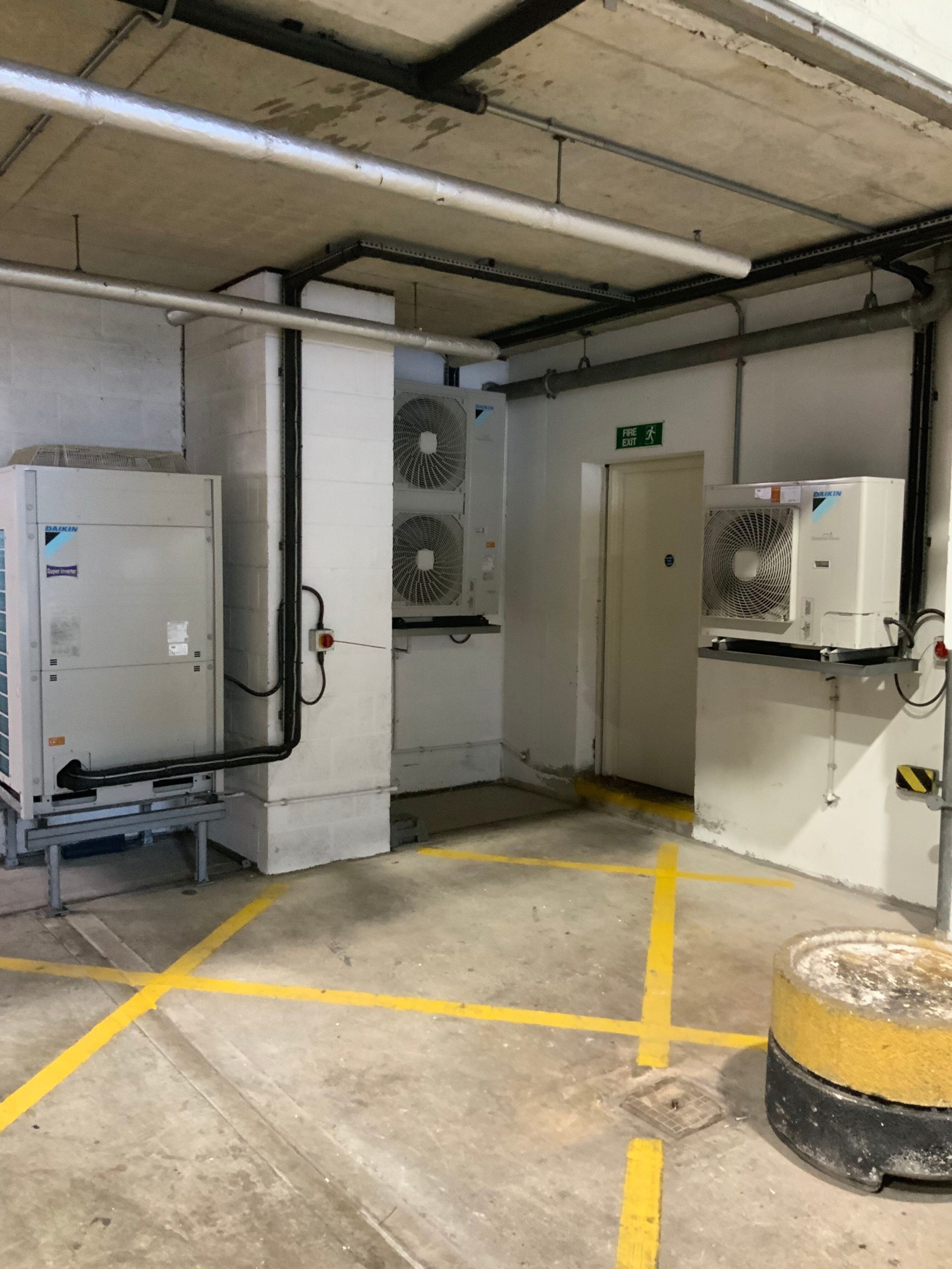 Indoor mechanical room with multiple Daikin HVAC units installed on the floor and wall.